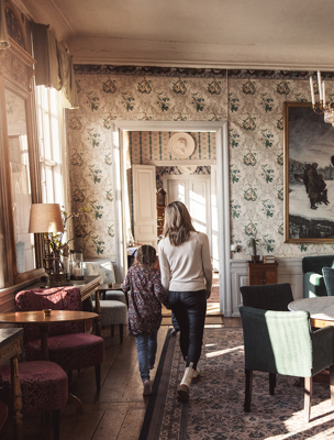 Mamma och dotter går genom vackra salonger i herrgården