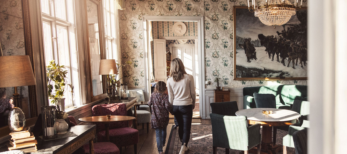Mamma och dotter går genom vackra salonger i herrgården