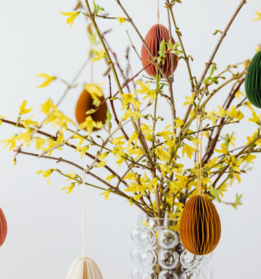 Påskdekorationer av papper hänger i ett påskris