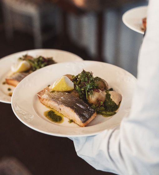Servitör serverar lax och potatis