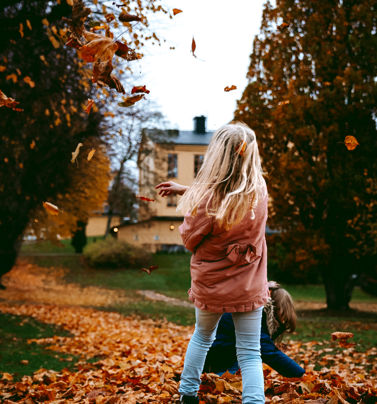 Barn leker i lövhög