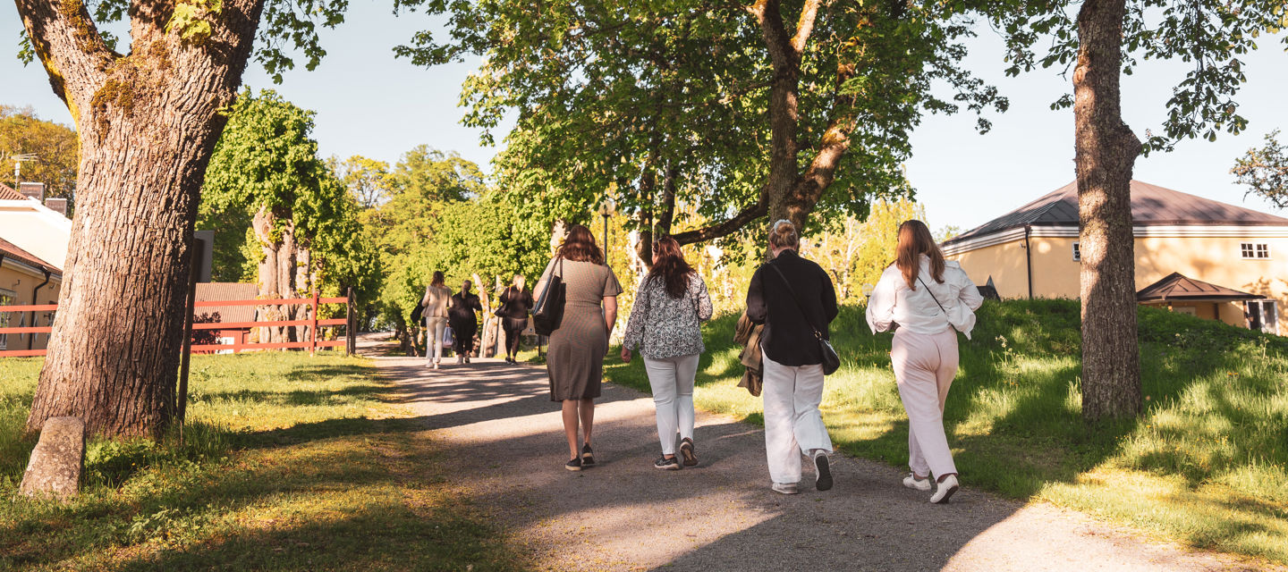 En grupp med gäster går genom trädgården
