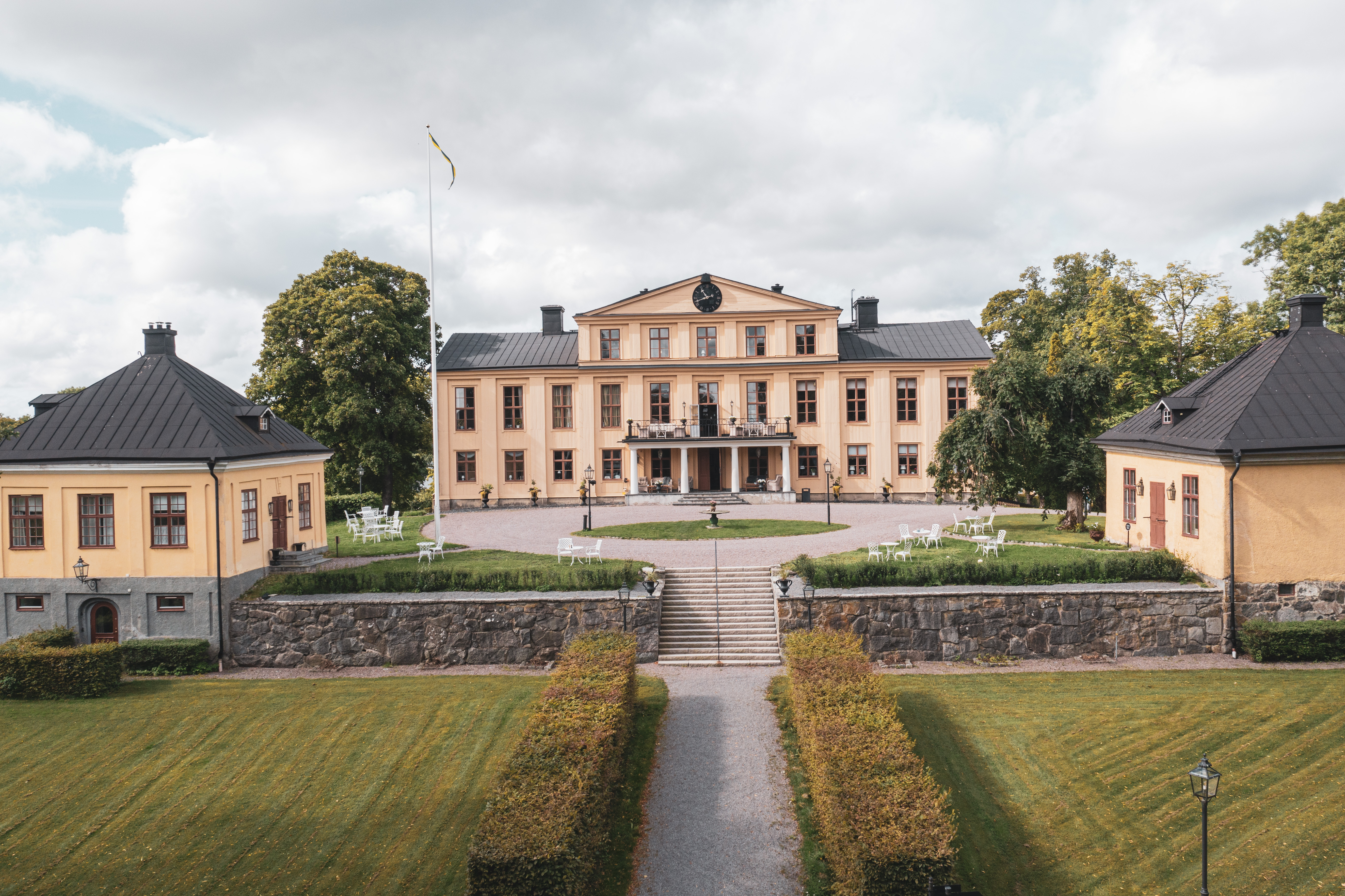Herrgårdsbyggnaden omgiven av grönskande miljöer
