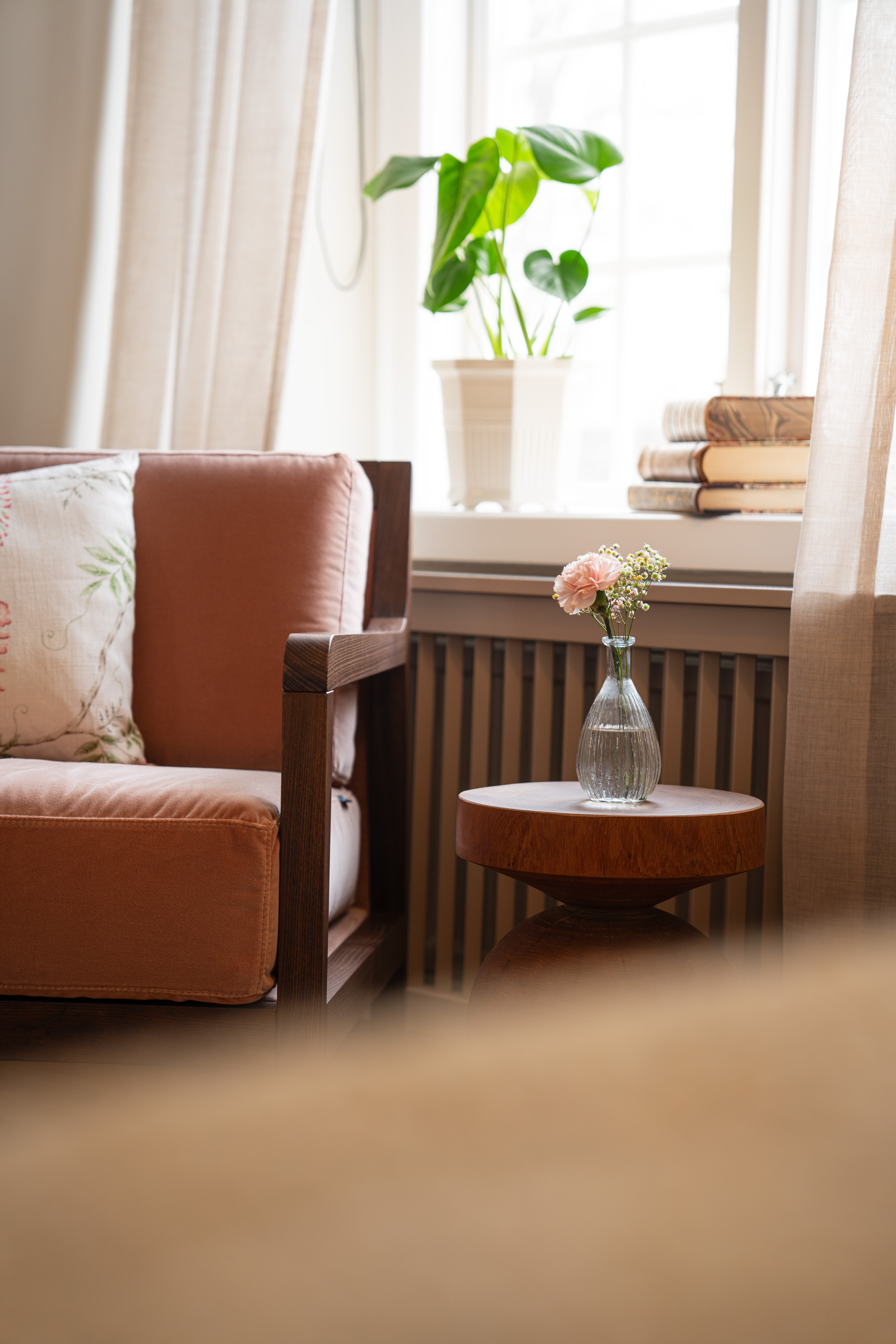 Skön fåtölj och på ett bord bredvid står en vas med färska blommor