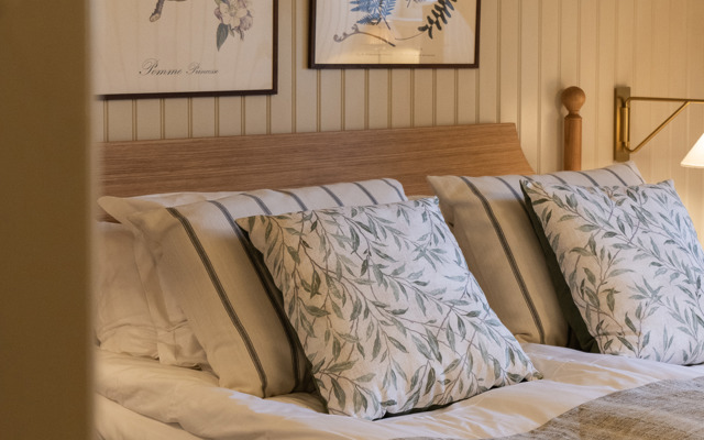 Bäddad säng med vackra prydnadskuddar i herrgårdsstil