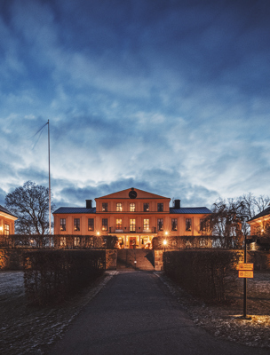 Herrgårdens fasad upplyst av lampor en höstkväll