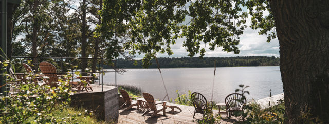 Uteplats med solstolar framför bastun som ligger vid vattnet