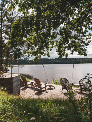 Uteplats med solstolar framför bastun som ligger vid vattnet