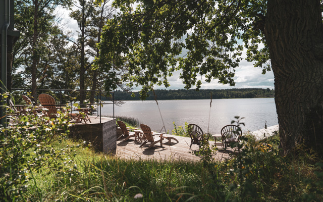 Uteplats med solstolar framför bastun som ligger vid vattnet