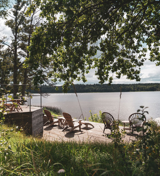 Uteplats med solstolar framför bastun som ligger vid vattnet