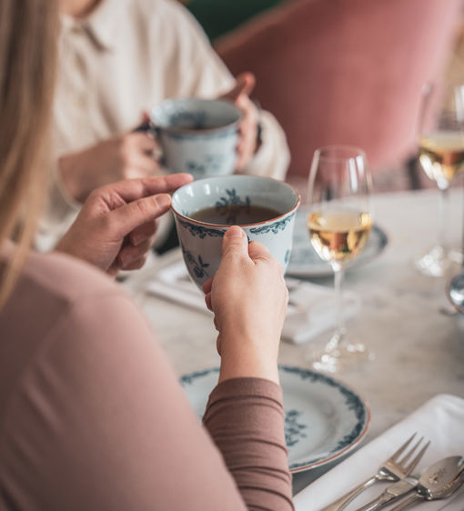 Två personer dricker te och champagne och avnjuter afternoon tea