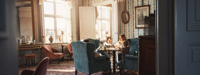 Familj spelar brädspel i en av herrgårdens vackra salonger