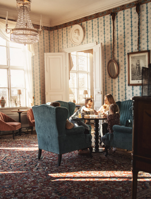 Familj spelar brädspel i en av herrgårdens vackra salonger