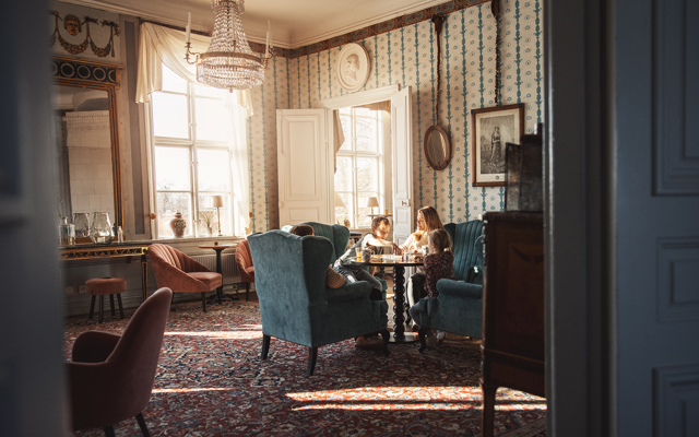 Familj spelar brädspel i en av herrgårdens vackra salonger