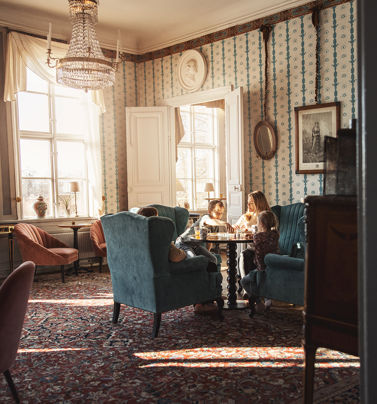 Familj spelar brädspel i en av herrgårdens vackra salonger