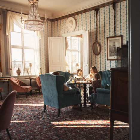 Familj spelar brädspel i en av herrgårdens vackra salonger