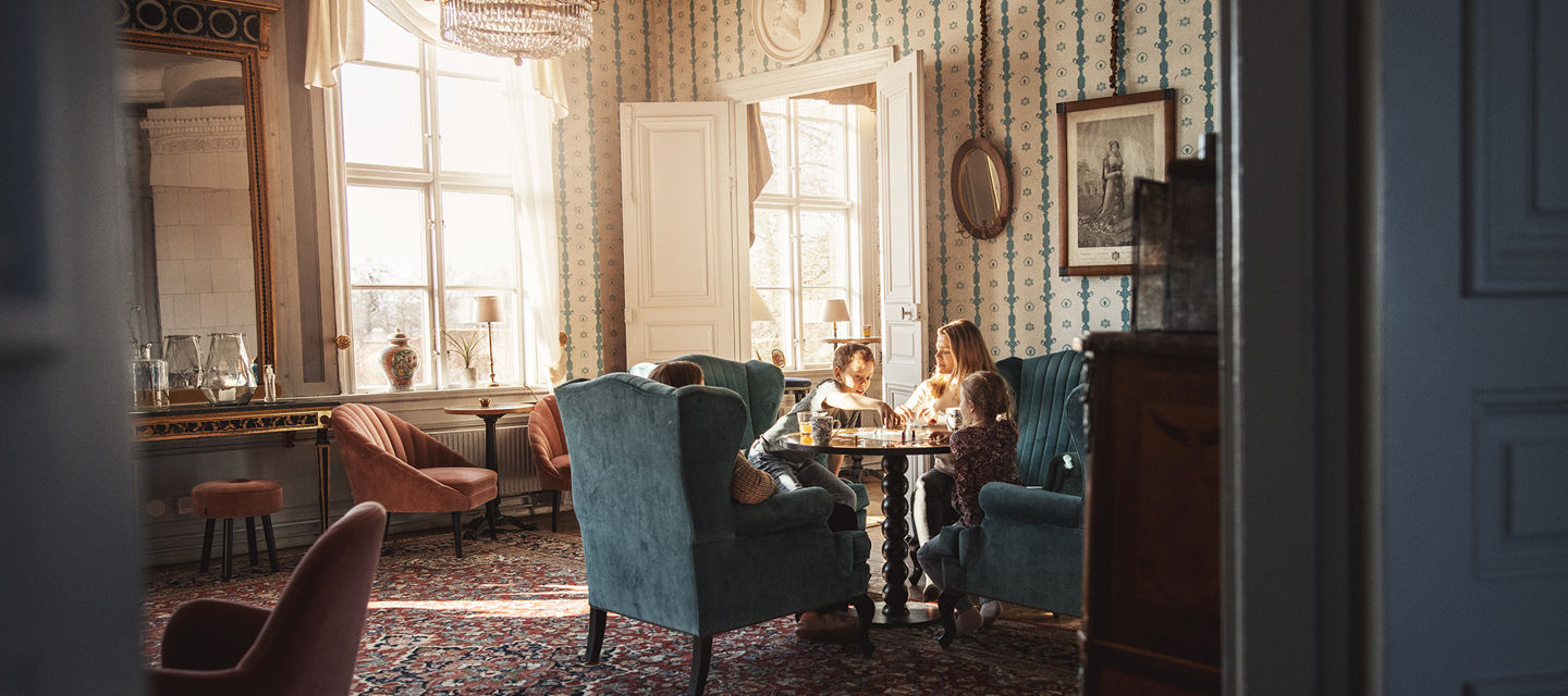 Familj spelar brädspel i en av herrgårdens vackra salonger