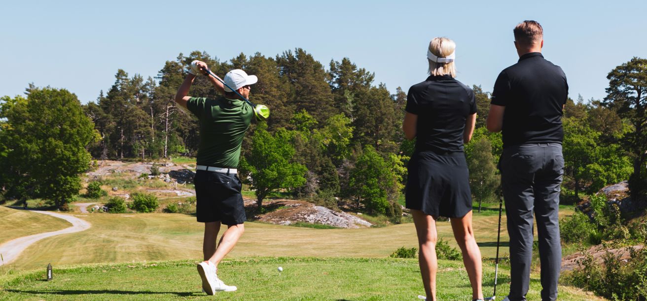 Tre personer på en golfbana