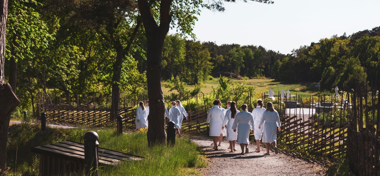 Grupp människor går i badrock mot havet